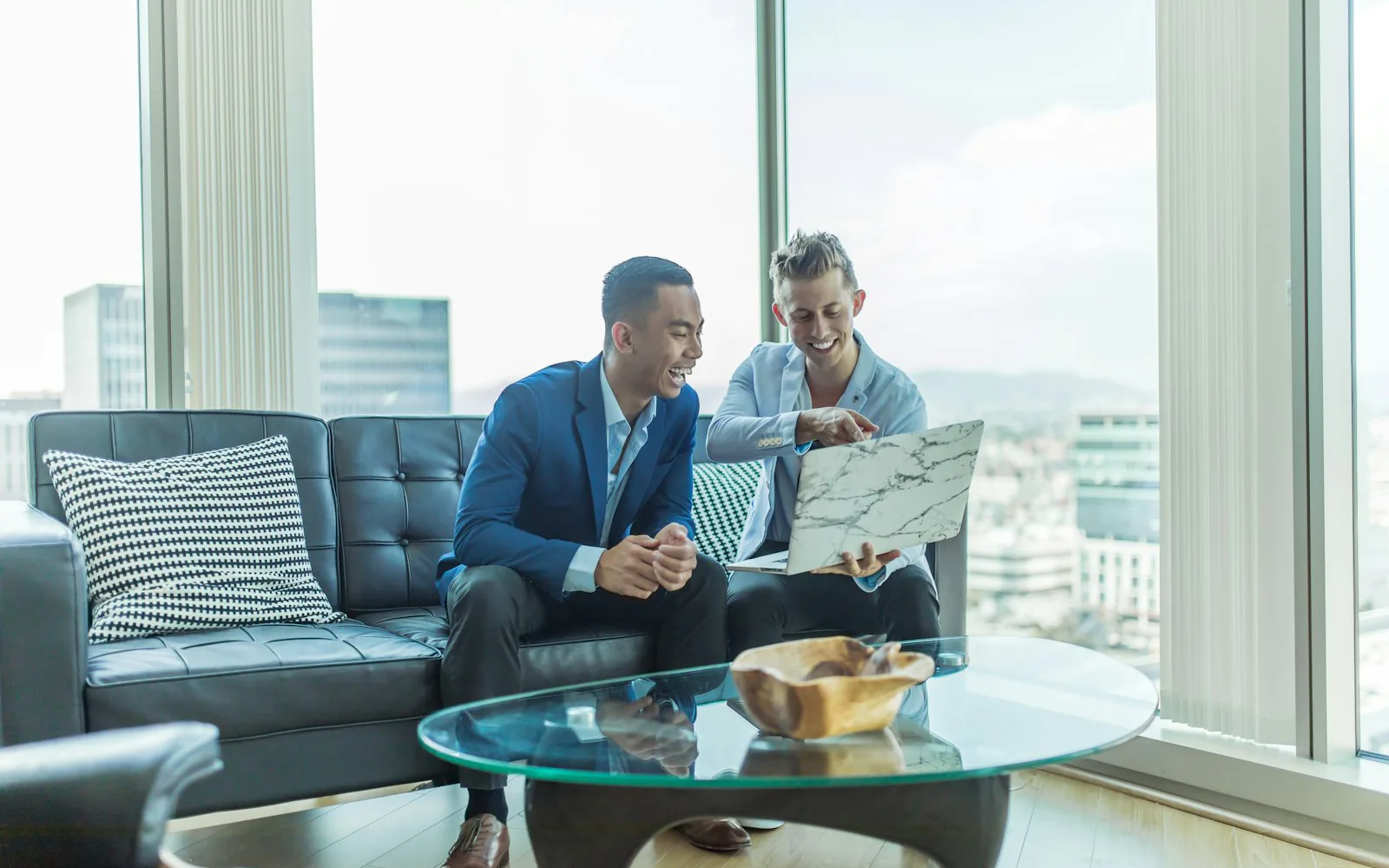 Two principals in discussion in a high-rise lounge overlooking a city skyline