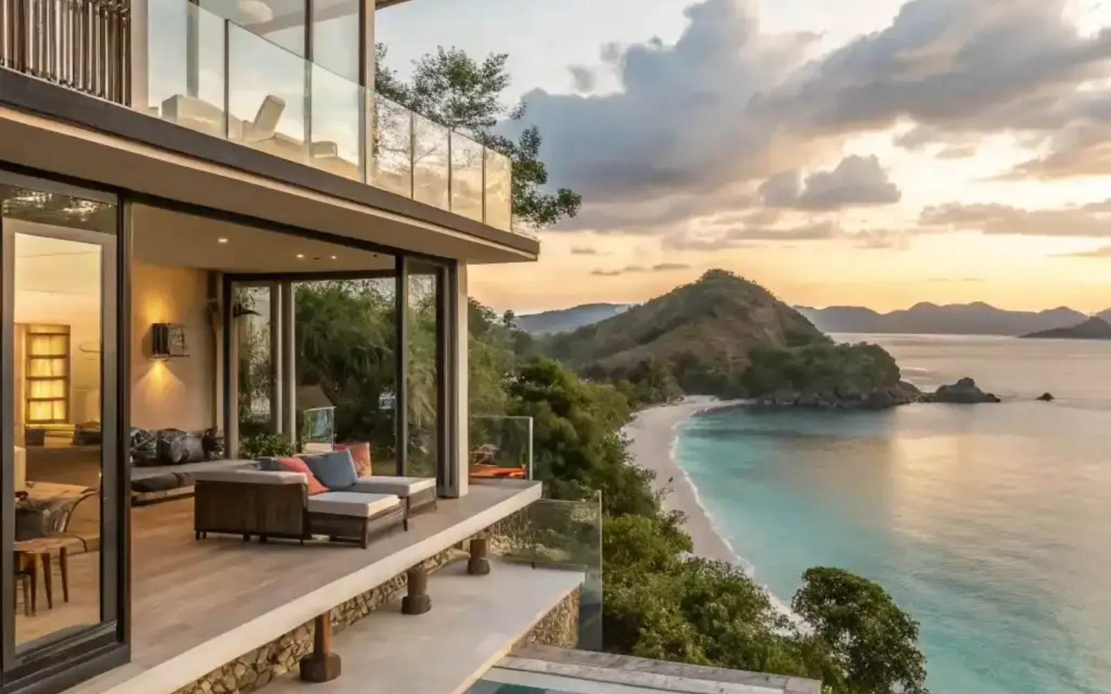 A clifftop villa terrace and living pavilion looking out over a bay at sunset