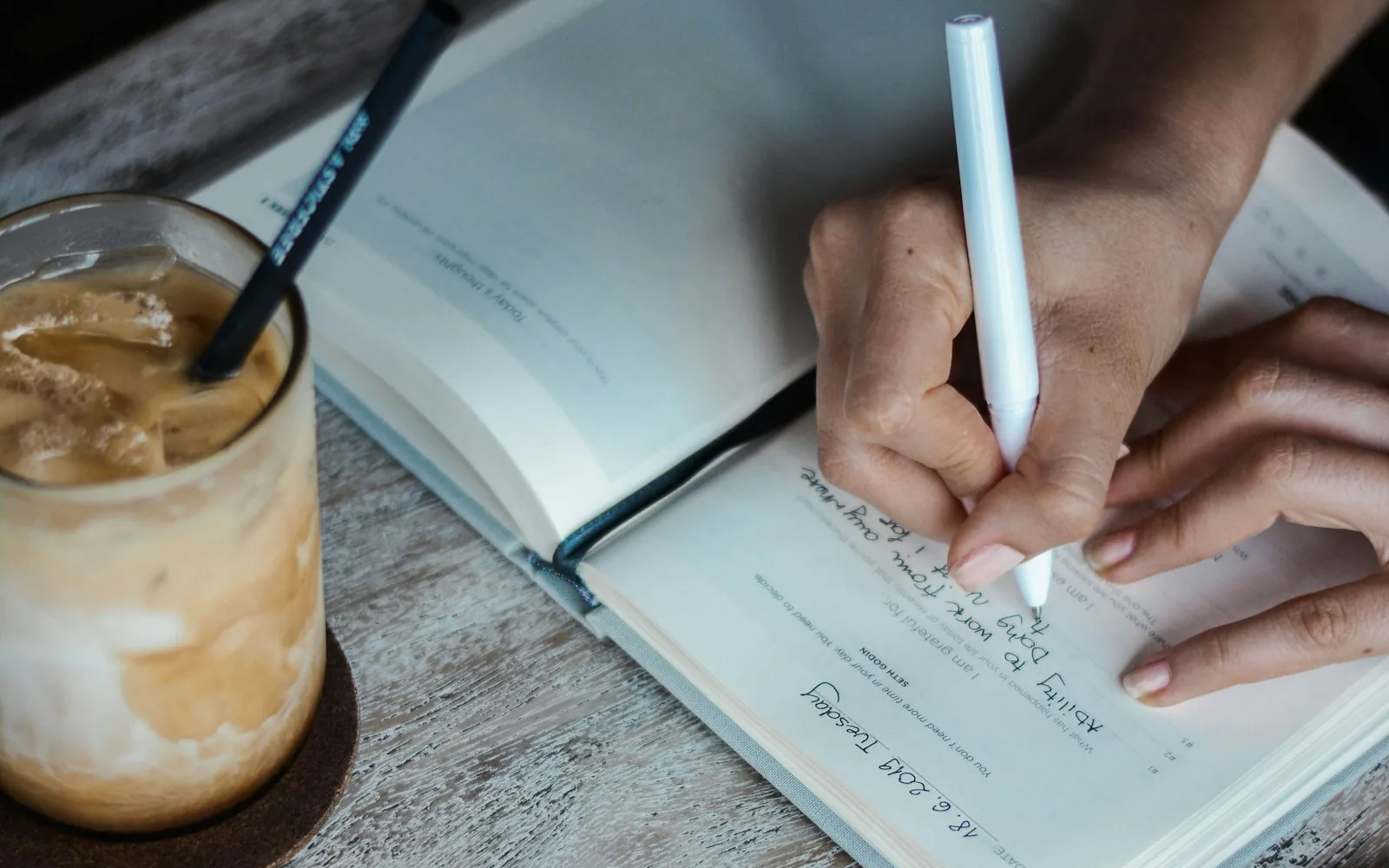 Handwritten briefing notes being taken in a journal beside a coffee
