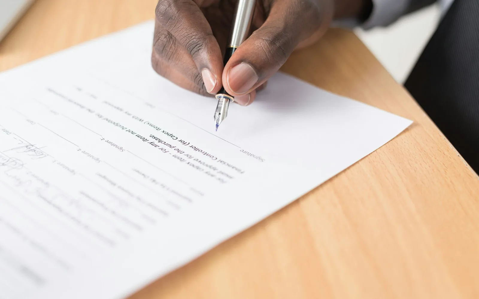 Two people reviewing and signing a printed document at a desk
