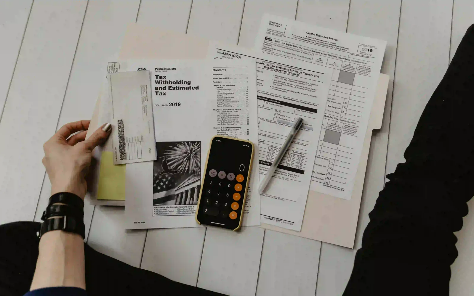 Tax forms, a calculator and working notes laid out on a desk